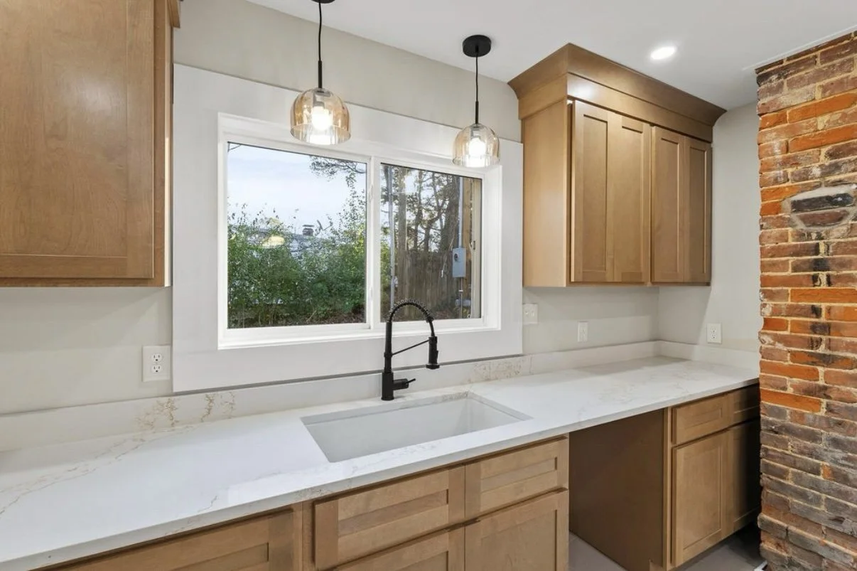 Kitchen sink wall with wood cabinets and pendant lights