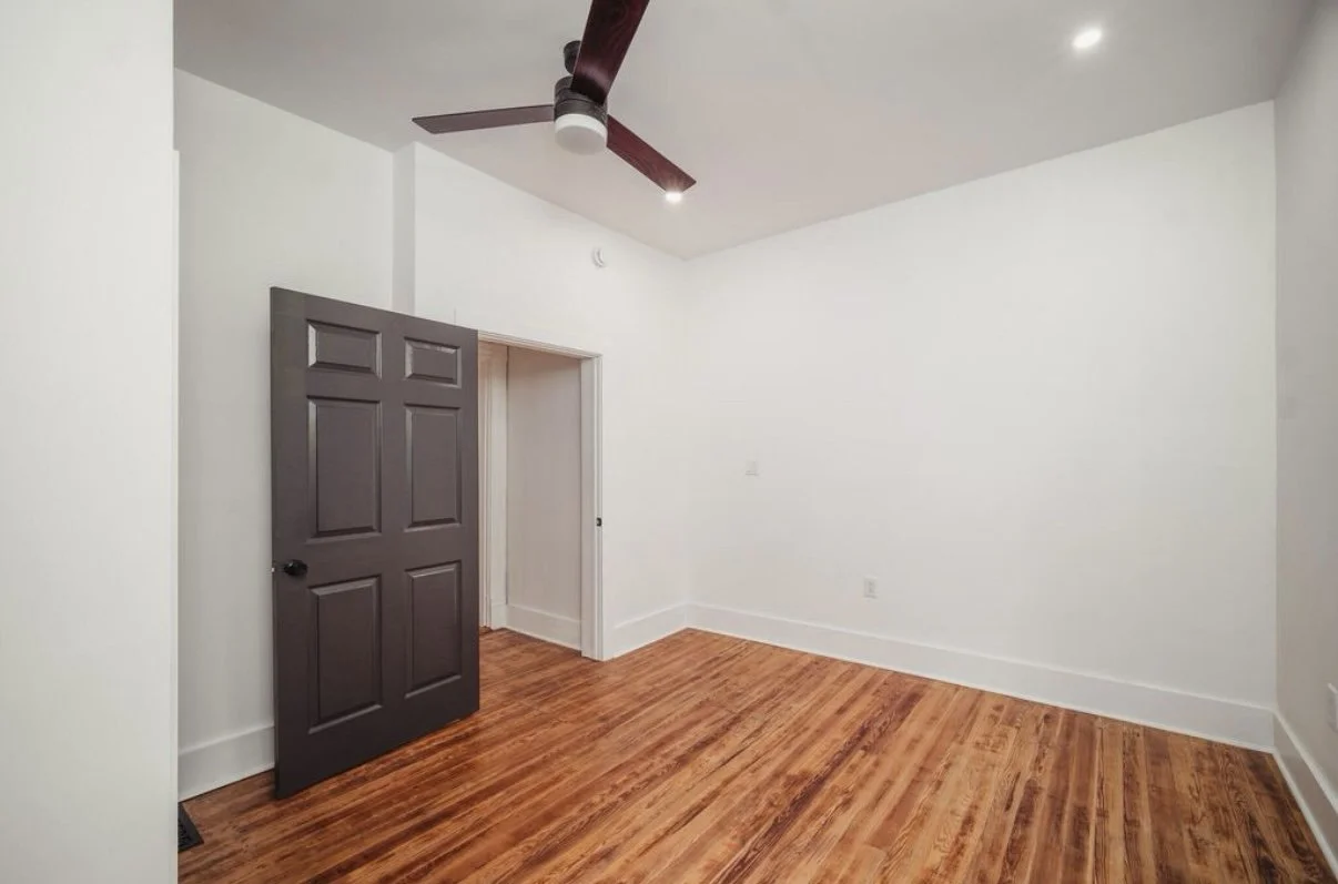 Bedroom with dark door and hardwood floors